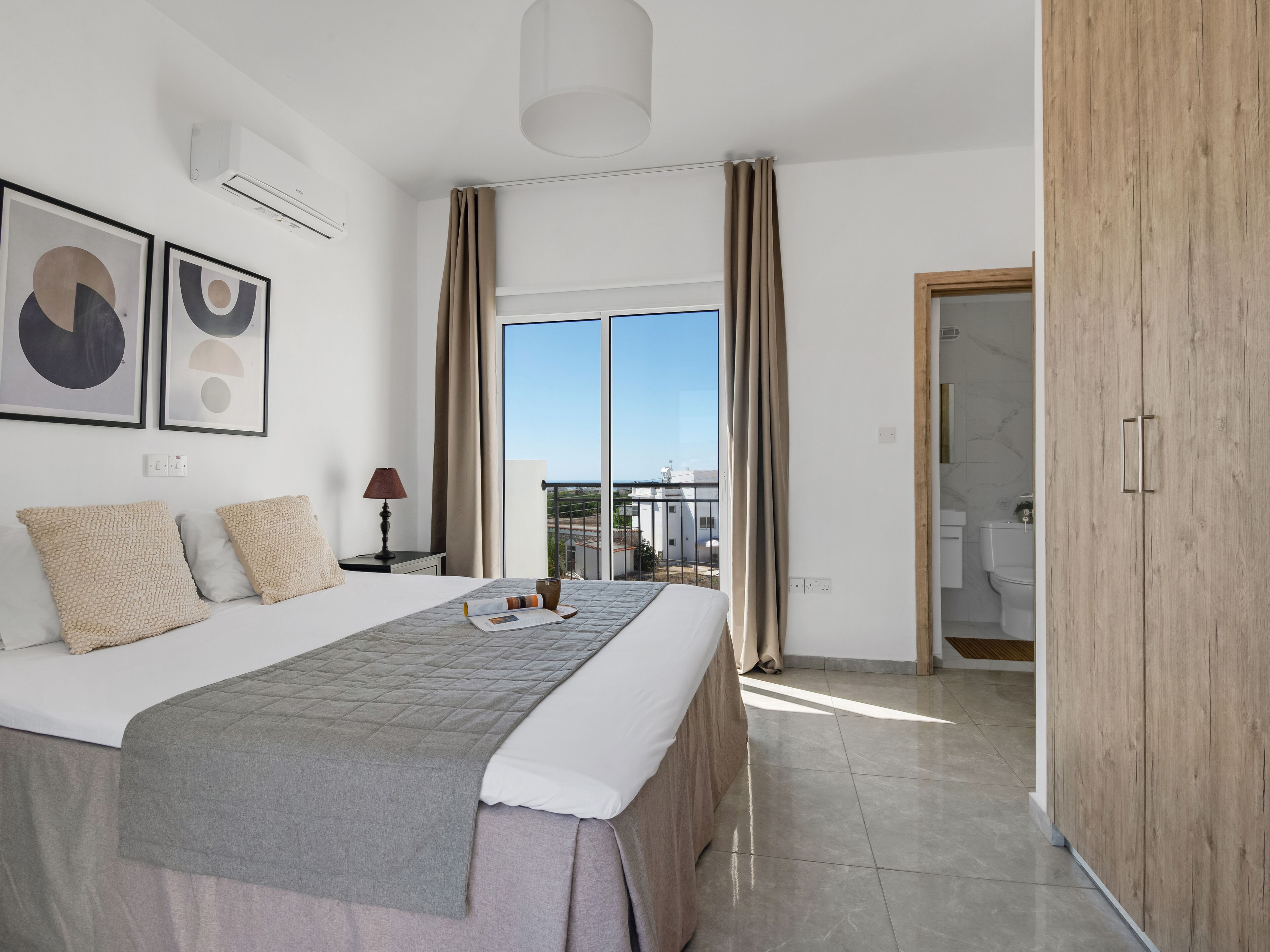 Una habitación de hotel moderna con una cama grande, vista a la ciudad y un armario de madera.