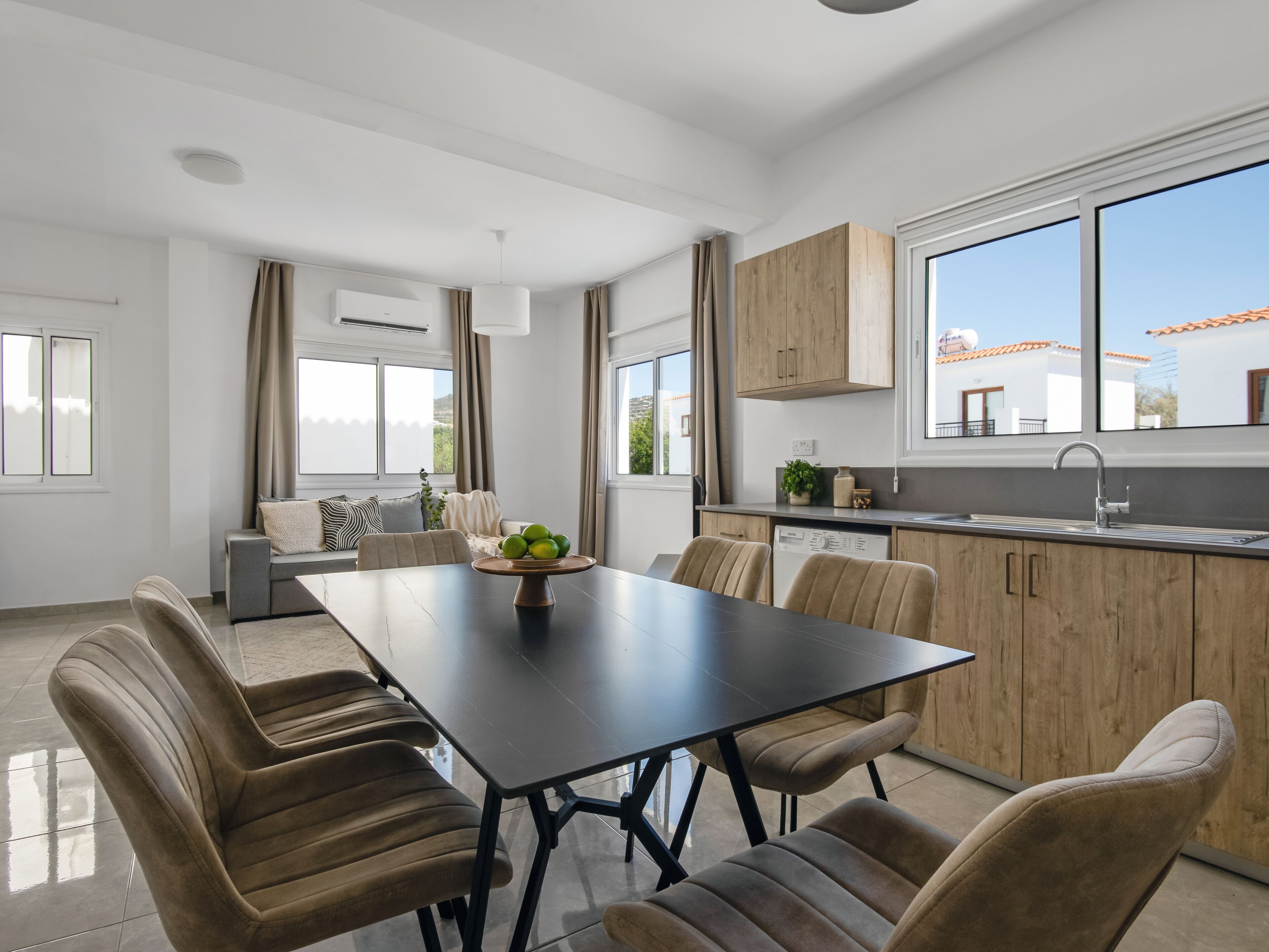 A modern kitchen with wooden cabinets, a black dining table, and a view of the outside.