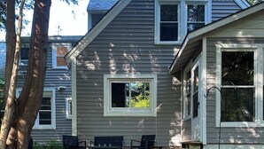 Une maison avec un chemin de gravier menant à un patio aménagé avec du mobilier d’extérieur.