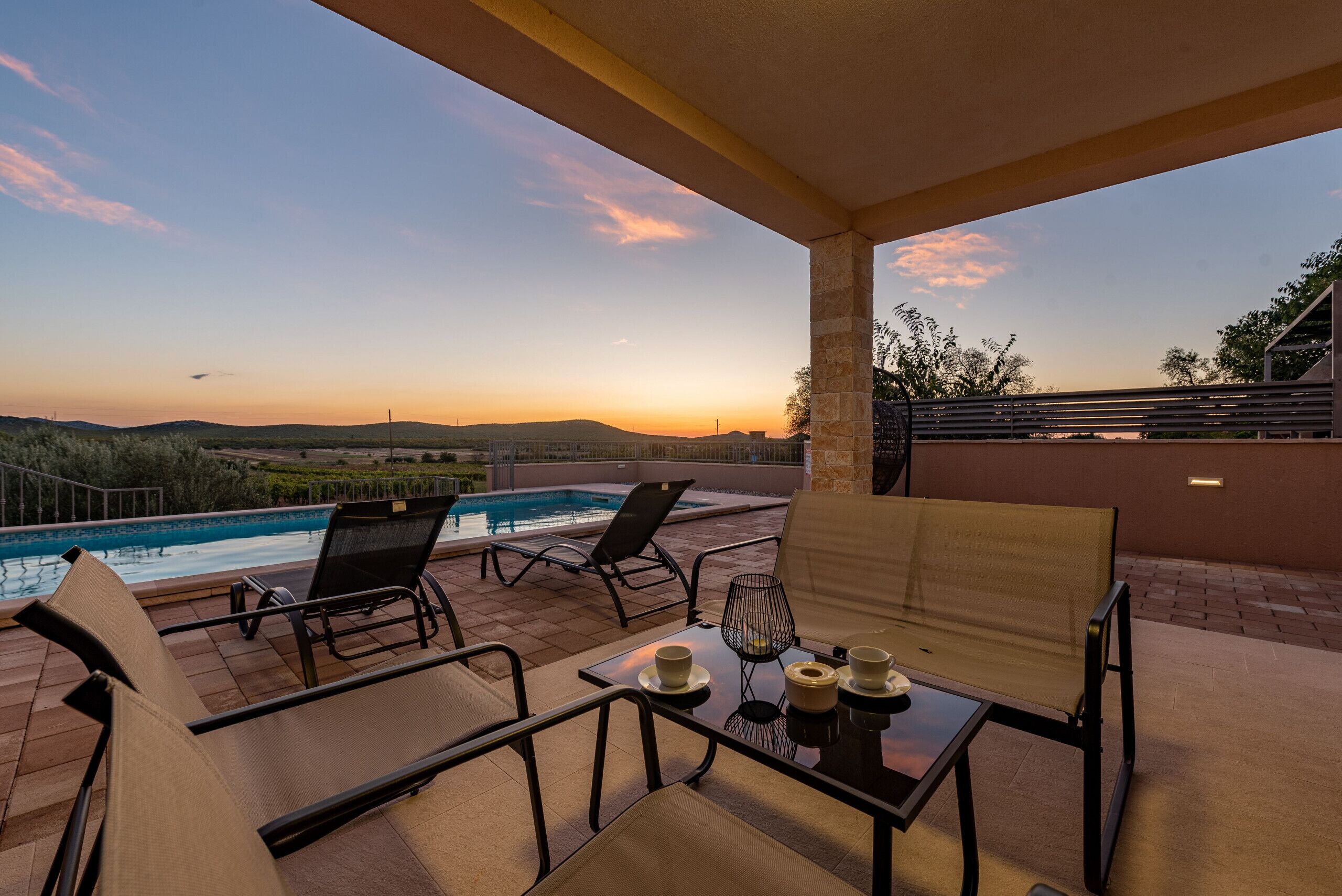 A rooftop terrace with a pool, lounge chairs, and a table with cups and a candle.