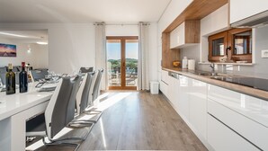A modern kitchen with white cabinets, a wooden countertop, and a view of the outdoors.