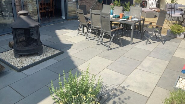 Een terras buiten met vuurkorf, zitgedeelte en barbecue.