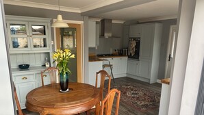 Een eethoek met een ronde houten tafel, vier stoelen en een vaas met gele bloemen.