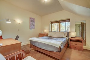 A bedroom with a bed, bedside tables, a desk, and a window with curtains.