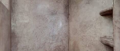 A bathroom with a textured wall, a shower area, and a wooden door.