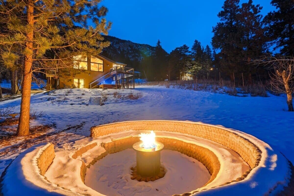 A snow-covered outdoor area with a circular fire pit in the center, surrounded by snow.