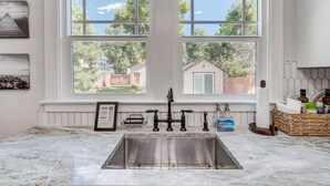 A kitchen with a large window, a stainless steel sink, and a marble countertop. - 3BD Cottage Backyard near Garden of the Gods in CO (Colorado Springs)