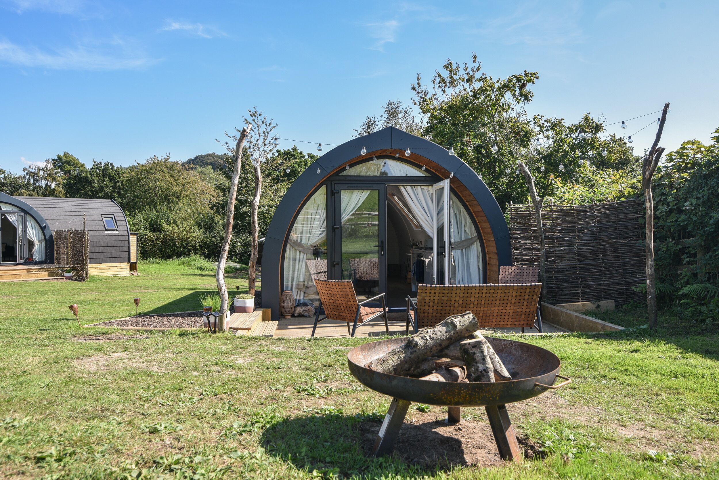 A cozy outdoor seating area with a fire pit, a covered patio, and a small garden.