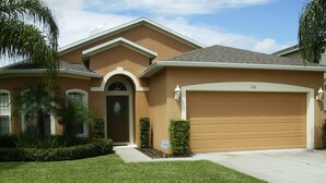 A residential house with a brown facade, a garage, and a well-maintained lawn. - 4 Bedroom - Budget Home with Private Pool (Clermont)