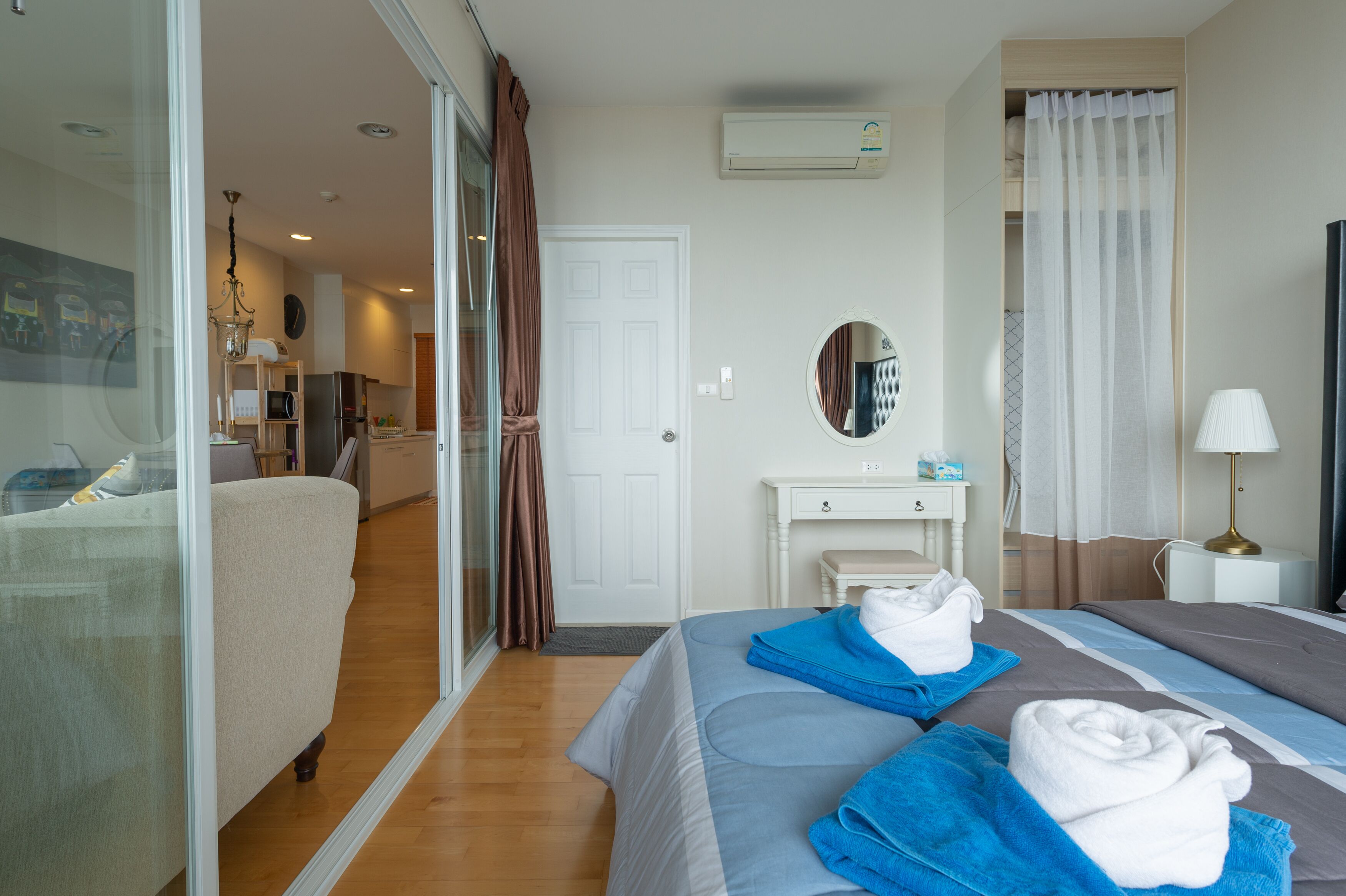 Une chambre d’hôtel avec un lit, un bureau, un miroir et une salle de bain visible à travers une porte en verre.