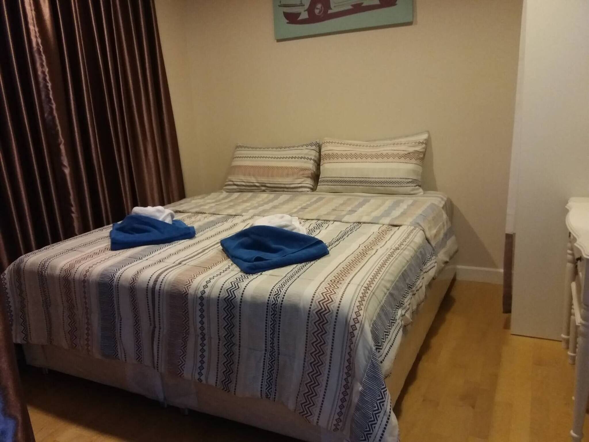 Una cama con ropa de cama estampada y dos toallas azules dobladas.