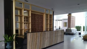 A reception area with a wooden reception desk, glass partitions, and a seating area with a sofa and chairs.