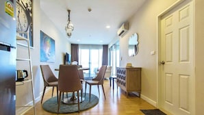 A hotel room with a dining area, a chandelier, a clock, and a door.