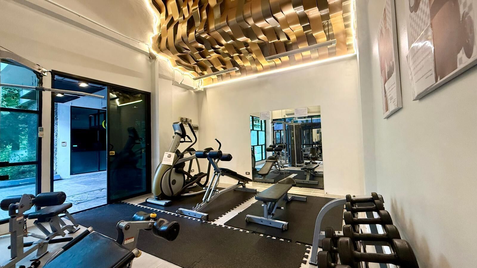 Un gimnasio con equipo de ejercicio, una cinta de correr y un espejo que refleja el espacio.