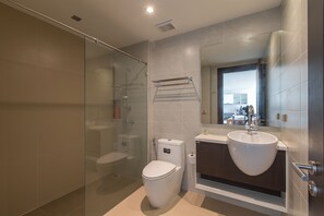A modern bathroom with a glass shower enclosure, a toilet, a sink, and a mirror. - Luxurious 4-Bedroom Apartment with Stunning Patong Bay Views (Pa Tong)