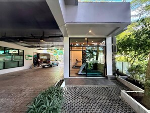 A modern building with a covered entrance, a treadmill, and a vehicle outside. - Luxurious 4-Bedroom Apartment with Stunning Patong Bay Views (Pa Tong)