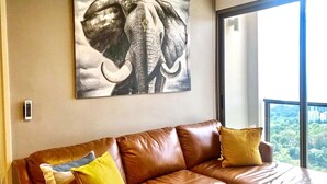 Ein braunes Ledersofa mit gelben Kissen und einem großen Elefantenbild an der Wand.