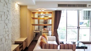 A modern hotel room with a sofa, a dining area, and a large window with a view.