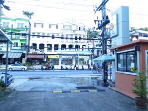 Cena de rua com uma loja FamilyMart, motocicletas estacionadas e um abrigo de ponto de ônibus.