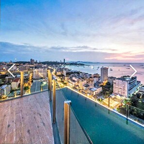 Una propiedad frente al agua con piscina, vistas de la ciudad y un atardecer.