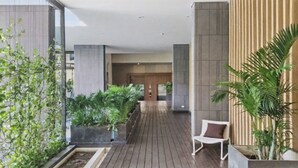 A modern corridor with wooden flooring, potted plants, and a white chair. - S39- 1 BR Downtown Bangkok Apt with Balcony and Pool (Krung Thep Maha Nakhon)
