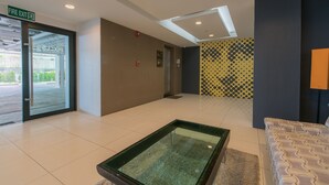 A hotel lobby with a glass table, a fire exit sign, and a patterned wall. - Pixel-Modern 1-BR Apartment with Pool View in Cape Panwa (Wichit)