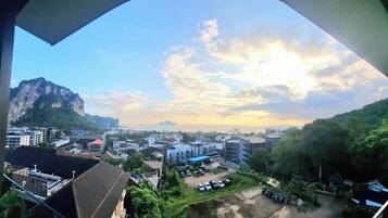 A view of a coastal cityscape with buildings, a mountain, and a sunset.