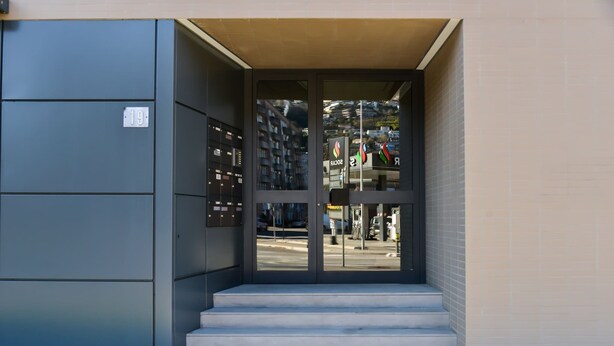 A building entrance with a set of stairs leading up to a glass door. - Central Plaza Apartment 1 in Lugano (Lugano)