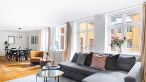 A modern living room with a grey sofa, round coffee table, and dining area with a table and chairs. - City 1- Pleasant 4-Bdr Apt in Central Copenhagen (København)