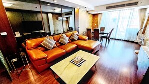 A modern living room with a leather sofa, a coffee table, a TV, and a dining area.