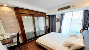 A hotel room with a bed, a desk, and a sliding glass door leading to a balcony.
