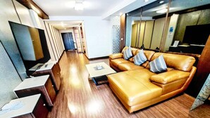 A modern living room with a leather sofa, a flat-screen TV, and a wooden floor.