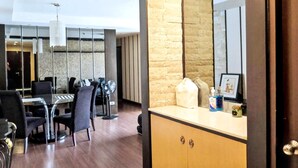 A modern hotel room with a wooden cabinet, a glass table, and chairs.