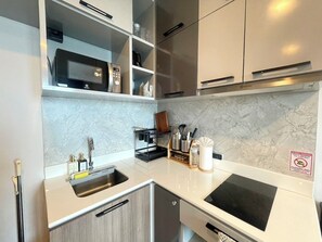 A modern kitchen with a double sink, stainless steel appliances, and a marble backsplash.