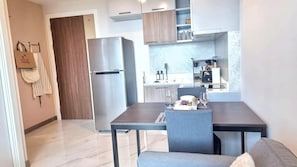 A modern kitchen with a refrigerator, a dining table with chairs, and a small island with a sink.