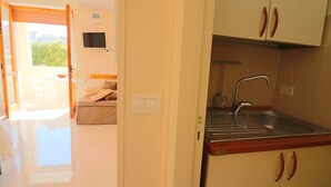 Una cocina con un lavamanos, armarios y un televisor montado en la pared.