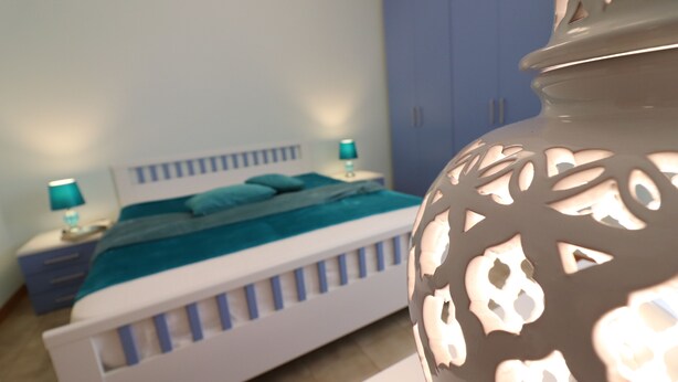 A bedroom with a bed, a nightstand, a lamp, and a decorative vase.