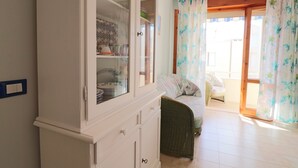 A room with a white cabinet, wicker furniture, and a view through a glass door.