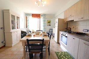 A kitchen with a dining table, chairs, cabinets, and an oven.