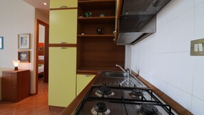 A kitchen with a gas stove, wooden cabinets, and a tiled backsplash.