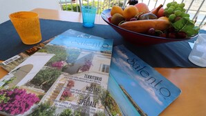 A table with a magazine, a bowl of fruit, and two glasses.