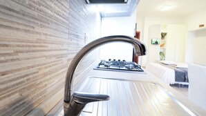 Una cocina con diseño moderno, que incluye un grifo de acero inoxidable y una estufa a gas.
