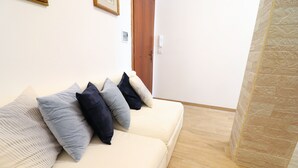 A room with a beige sofa, a wooden door, and a stone wall.