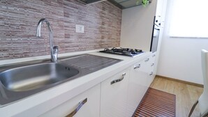 A modern kitchen with a stainless steel sink, a gas stove, and white cabinetry.