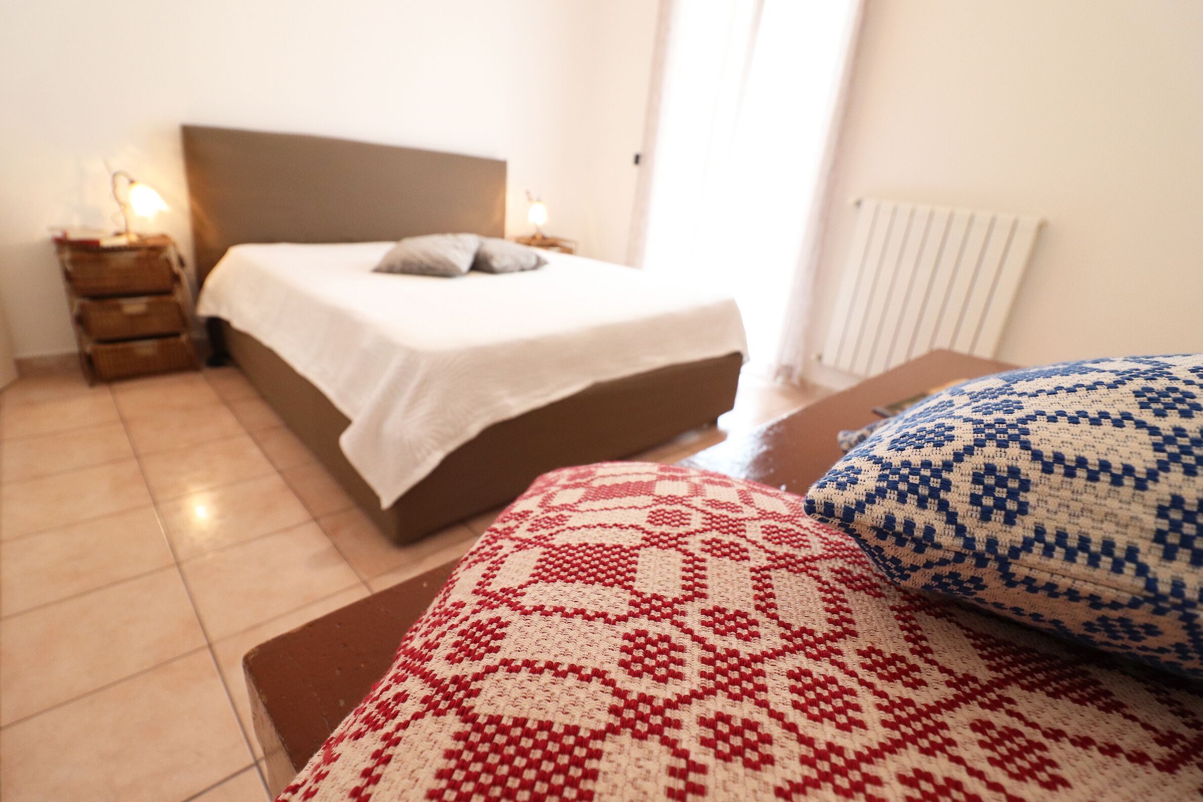 A bedroom with a bed, bedside tables, and a radiator.