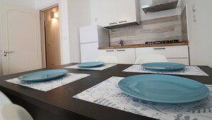 A modern kitchen with white cabinets, a stainless steel range hood, and a wooden countertop.