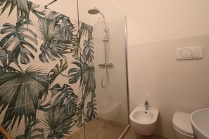 Een badkamer met een douche, toilet en hygiëneslot.