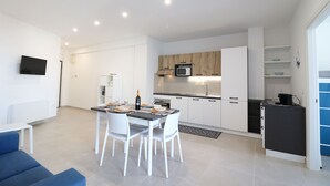 A modern kitchen with white cabinets, a microwave, and a dining area with a table and chairs. - Casa Galatea in the Center of Otranto (Otranto)