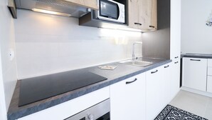 A modern kitchen with a built-in microwave, stainless steel appliances, and a black countertop. - Casa Galatea in the Center of Otranto (Otranto)
