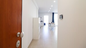 A hallway leading to a dining area with a table and chairs, a refrigerator, and a wall-mounted television. - Casa Galatea in the Center of Otranto (Otranto)
